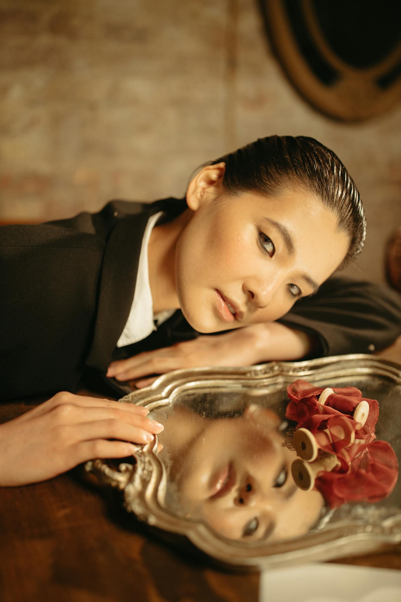 Stylish woman in a suit posing with a vintage mirror, capturing elegance and fashion.