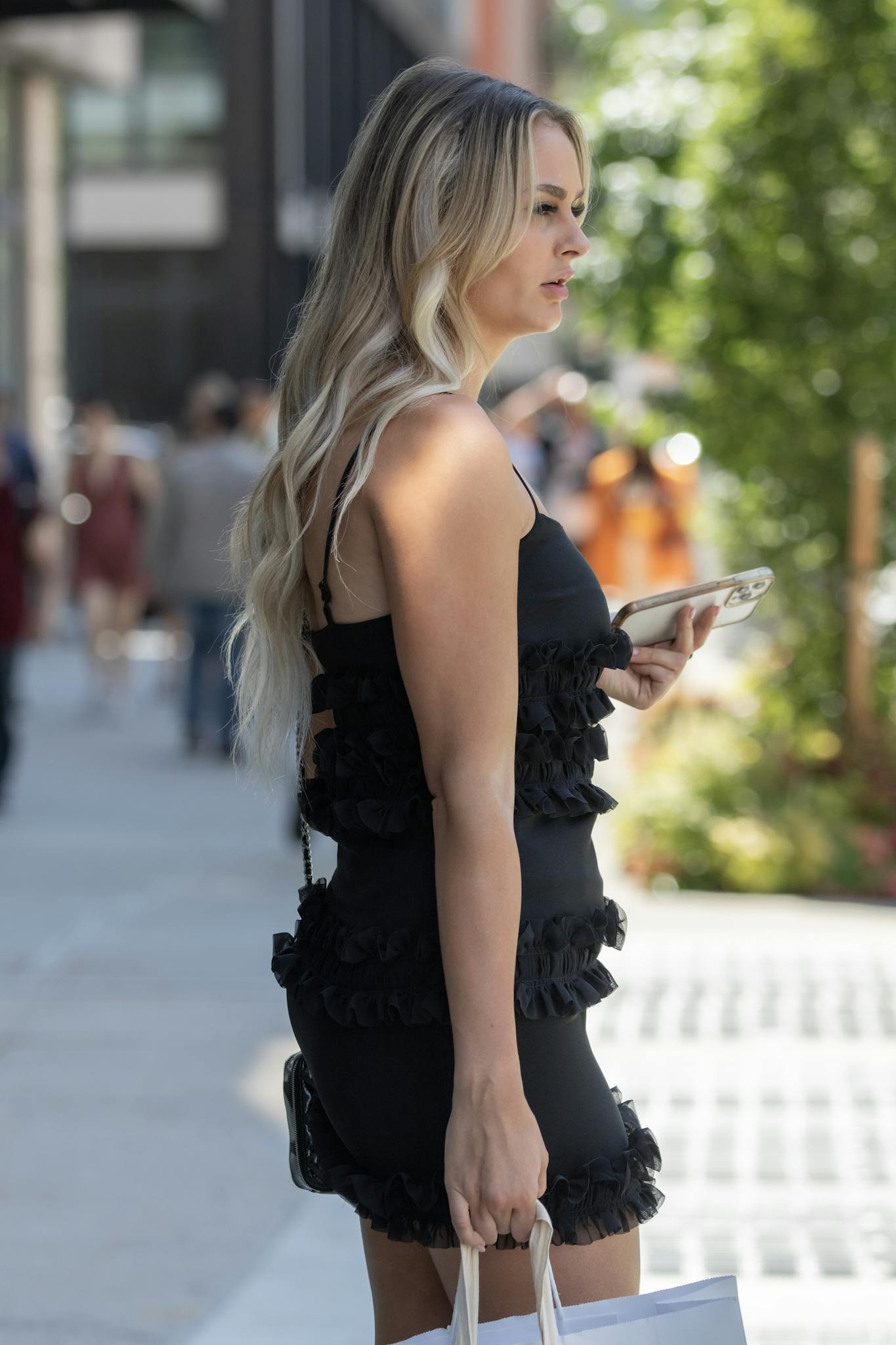 Stylish woman in a black dress on a busy New York sidewalk, showcasing chic fashion vibes.